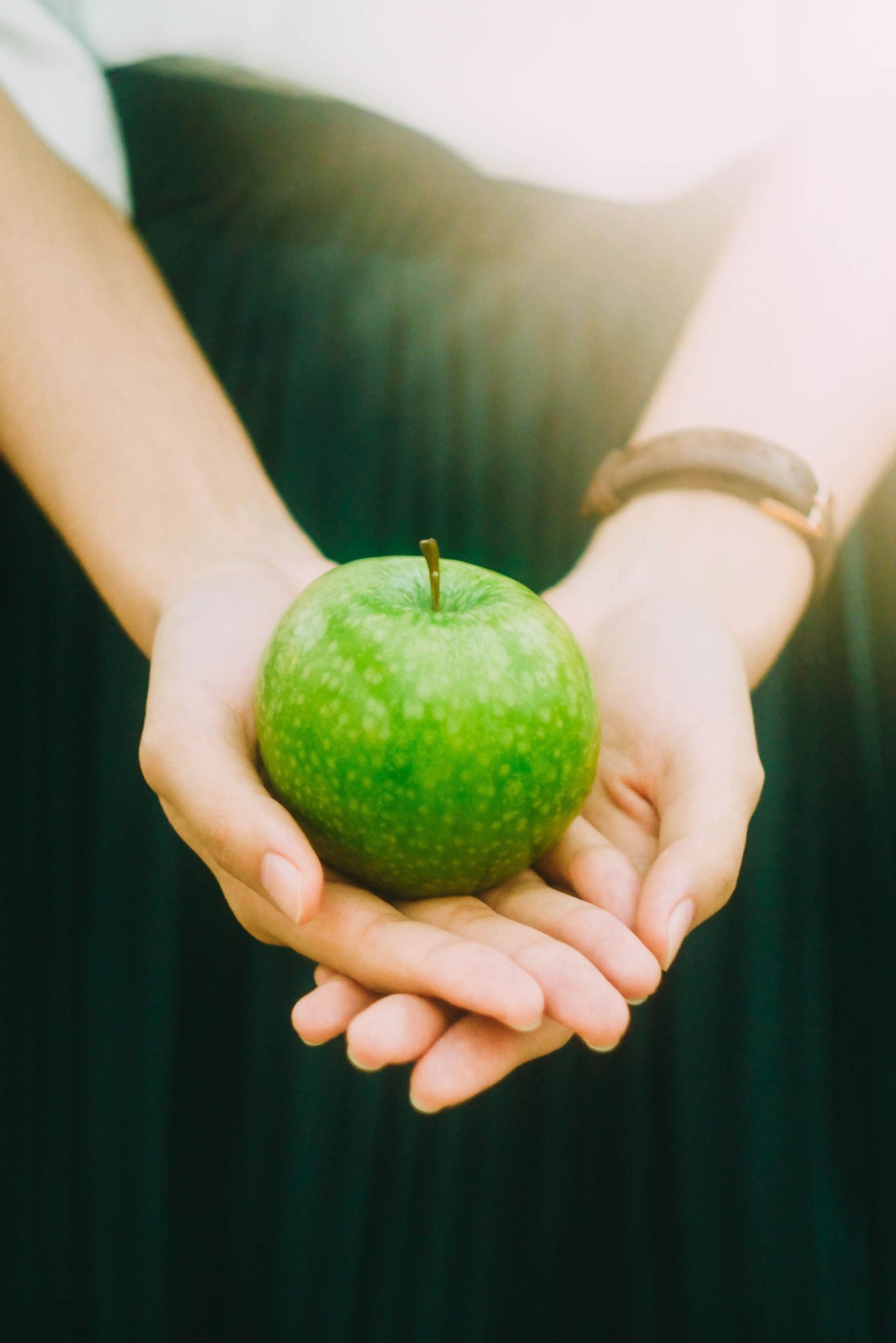 a hand holding a green apple